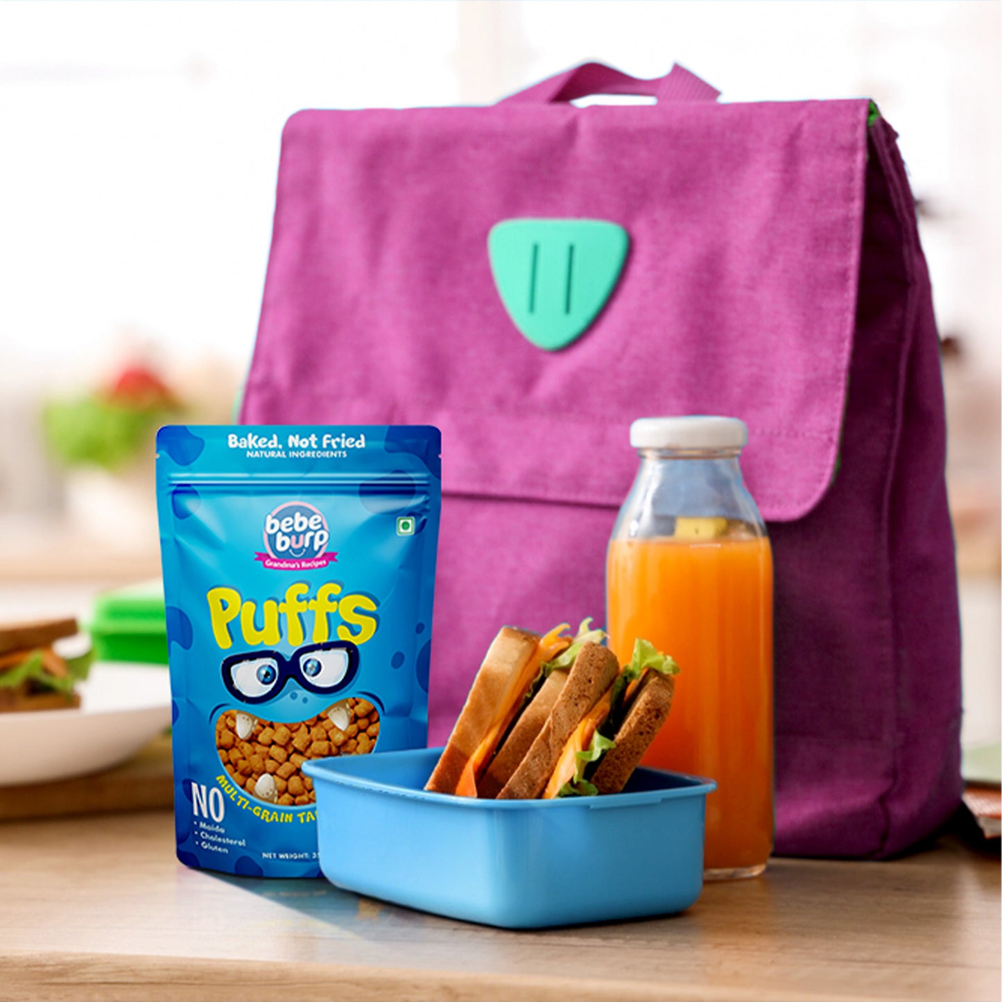Four packs of Bebe Burp Cheese Puff in multigrain tangy flavor, shown with grains like millet, corn, and lentils.